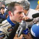Jacques Villenueve speaks to reporters after blowing a tire during the 1996 Japanese Grand Prix. Crucially, he does not appear to be singing.